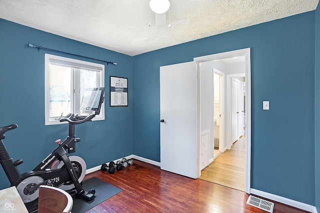 workout area featuring hardwood / wood-style floors and a textured ceiling