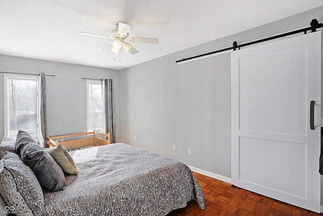 bedroom featuring dark parquet flooring, a barn door, and ceiling fan