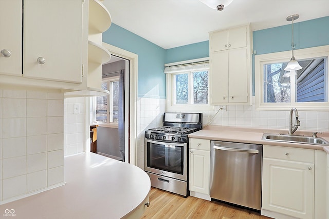 kitchen featuring appliances with stainless steel finishes, white cabinetry, plenty of natural light, and hanging light fixtures