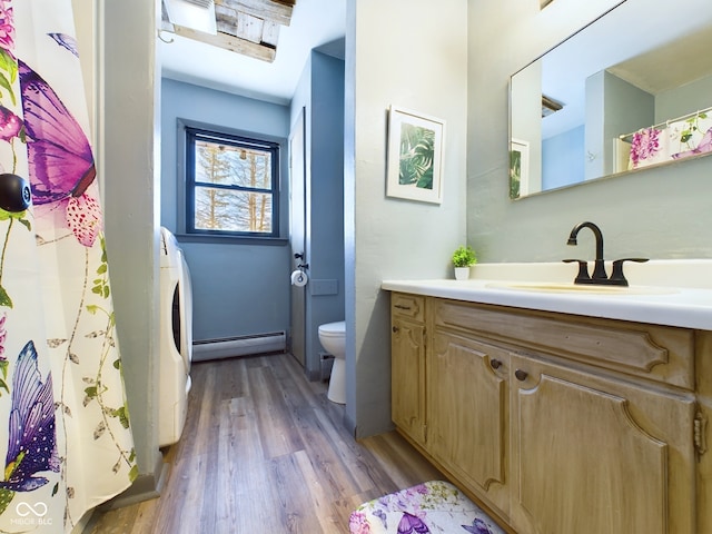 bathroom featuring washer / clothes dryer, hardwood / wood-style flooring, toilet, a baseboard heating unit, and vanity