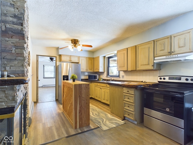 kitchen with appliances with stainless steel finishes, light hardwood / wood-style floors, decorative backsplash, a textured ceiling, and butcher block counters