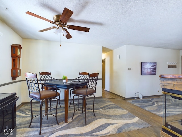 dining area featuring ceiling fan, dark wood-type flooring, and a textured ceiling