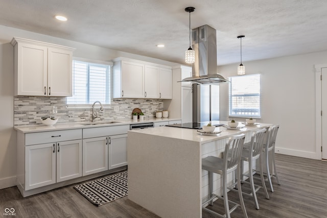 kitchen with sink, hanging light fixtures, white cabinetry, and island exhaust hood