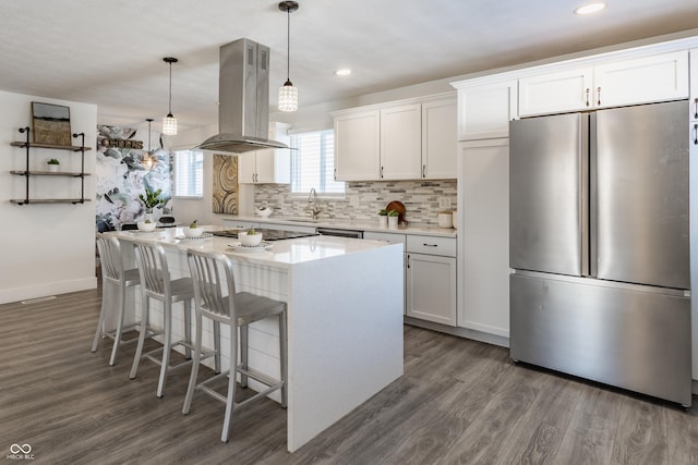 kitchen with decorative light fixtures, white cabinetry, island exhaust hood, and stainless steel fridge