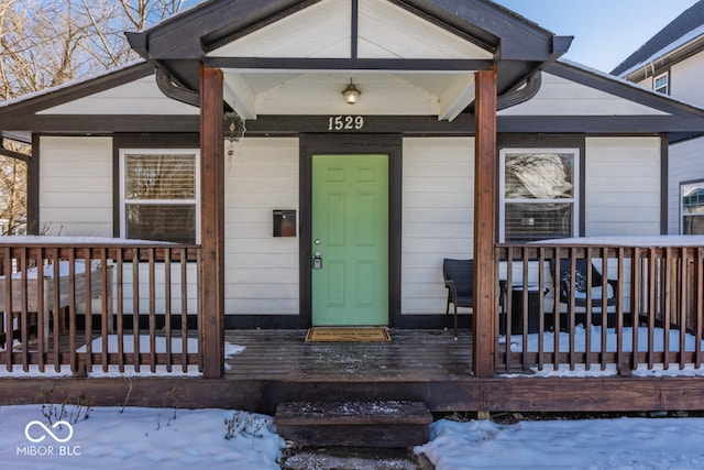 snow covered property entrance with a porch