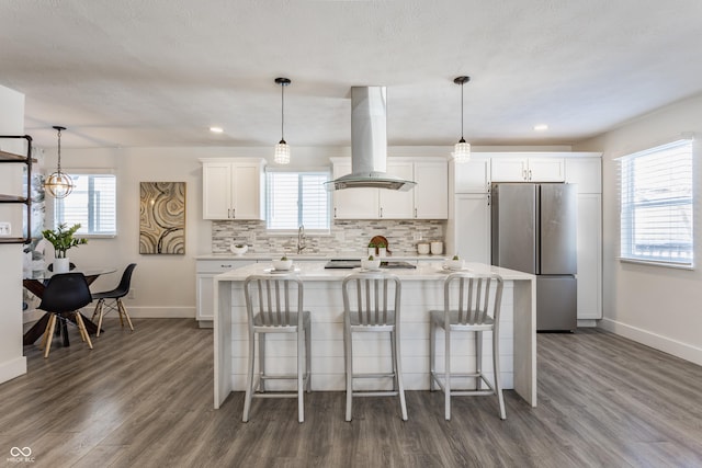 kitchen featuring stainless steel refrigerator, white cabinets, a kitchen island, and island exhaust hood