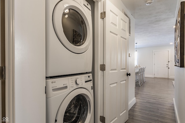 clothes washing area featuring dark hardwood / wood-style flooring and stacked washer / drying machine