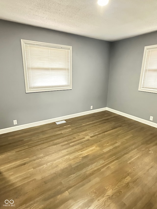 empty room with hardwood / wood-style floors and a textured ceiling