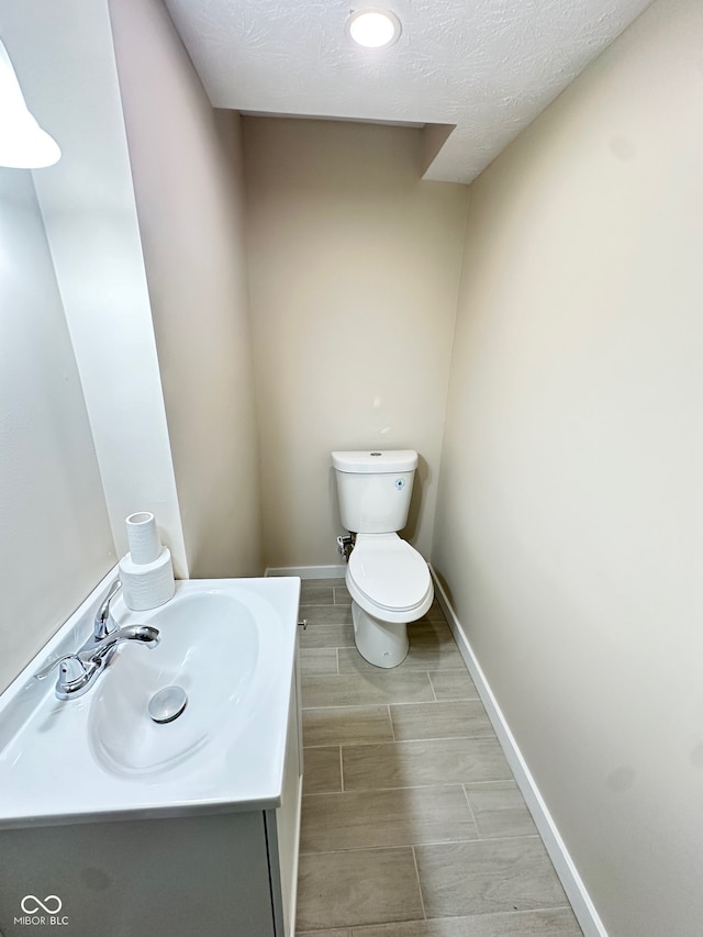 bathroom with vanity, a textured ceiling, and toilet