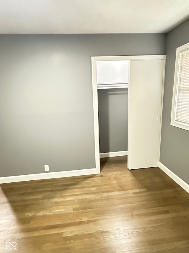 unfurnished bedroom with hardwood / wood-style flooring and a closet