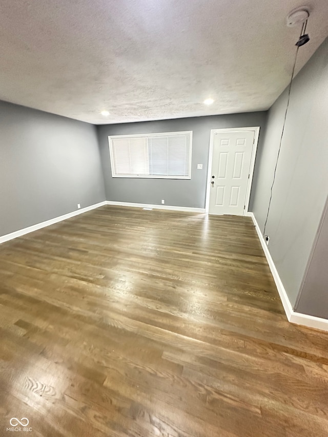 unfurnished room featuring dark hardwood / wood-style flooring and a textured ceiling