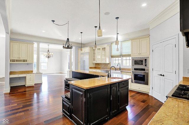 kitchen with a kitchen island with sink, an inviting chandelier, dark hardwood / wood-style floors, appliances with stainless steel finishes, and decorative light fixtures