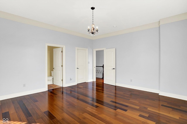 unfurnished bedroom featuring connected bathroom, hardwood / wood-style flooring, ornamental molding, and an inviting chandelier