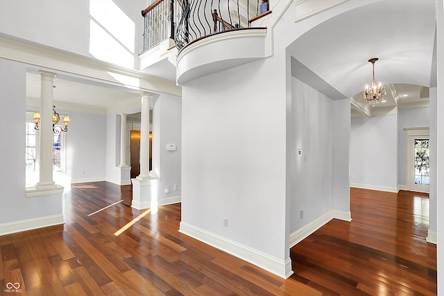 interior space with a high ceiling, dark hardwood / wood-style floors, ornate columns, and a notable chandelier