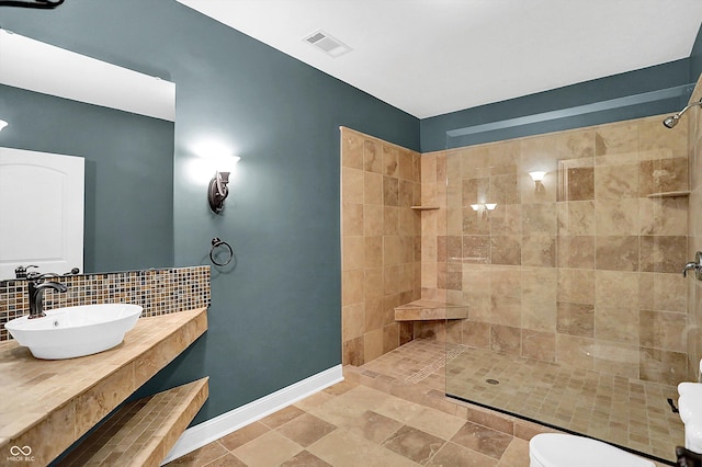 bathroom with backsplash, sink, and tiled shower