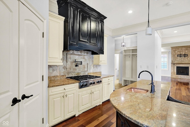 kitchen featuring stainless steel gas stovetop, sink, hanging light fixtures, decorative backsplash, and light stone countertops