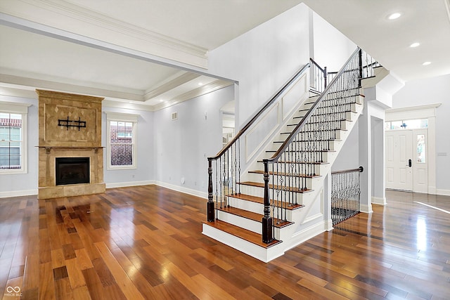 staircase with a fireplace, hardwood / wood-style flooring, and crown molding