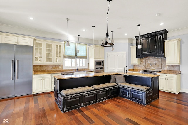 kitchen with a center island with sink, a breakfast bar, dark hardwood / wood-style flooring, and appliances with stainless steel finishes