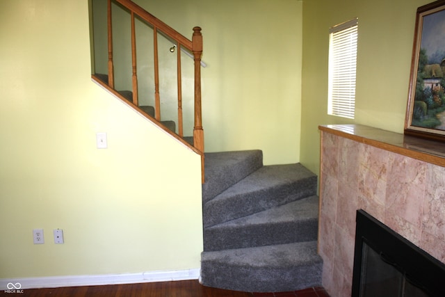 stairs with hardwood / wood-style flooring and a tile fireplace