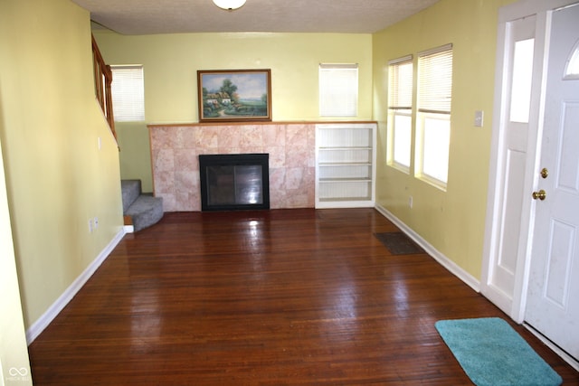 unfurnished living room with a fireplace, a textured ceiling, and dark hardwood / wood-style floors