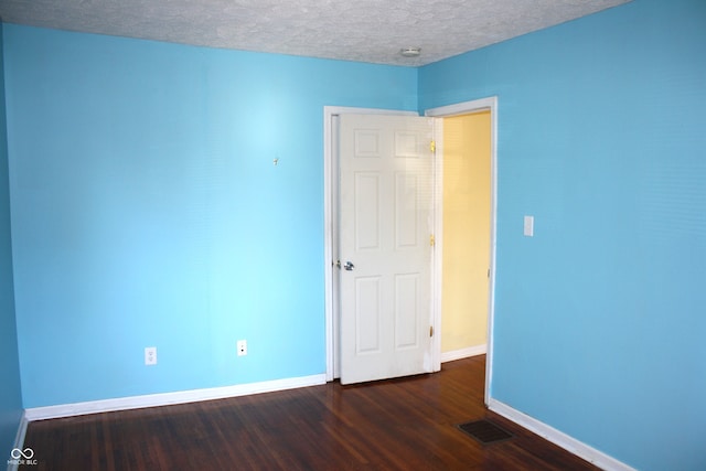 unfurnished room with dark wood-type flooring and a textured ceiling