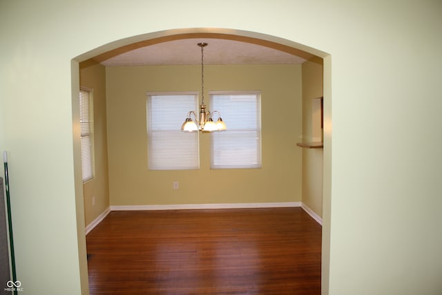 unfurnished dining area with a chandelier, dark wood-type flooring, and a textured ceiling