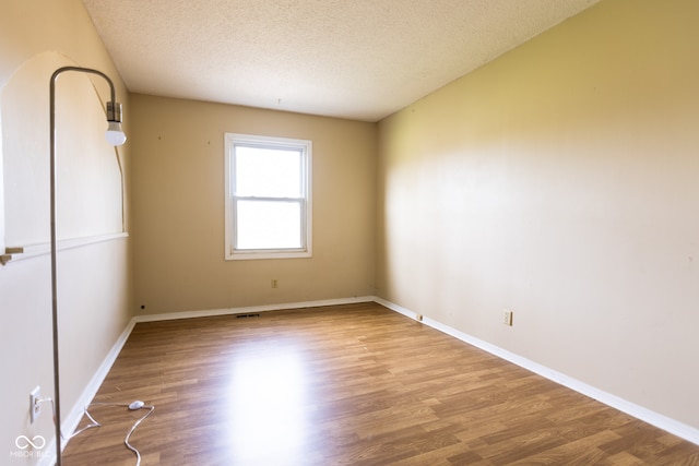 spare room featuring light wood-type flooring and a textured ceiling