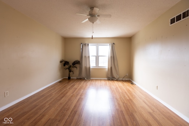 empty room with ceiling fan, light hardwood / wood-style flooring, and a textured ceiling