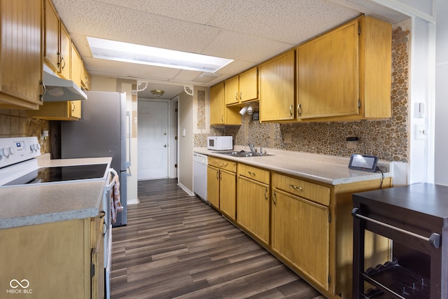 kitchen with sink, a drop ceiling, dark wood-type flooring, backsplash, and white appliances