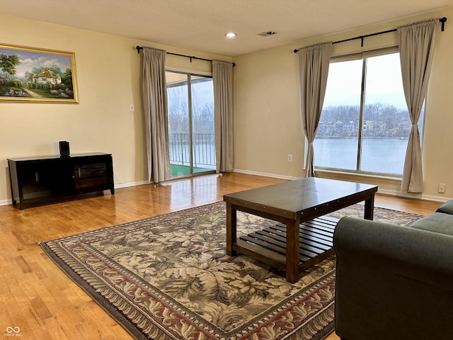 living room with hardwood / wood-style floors, a healthy amount of sunlight, and a water view