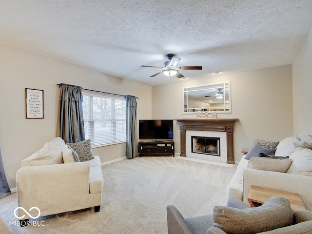 carpeted living room with a tile fireplace, ceiling fan, and a textured ceiling