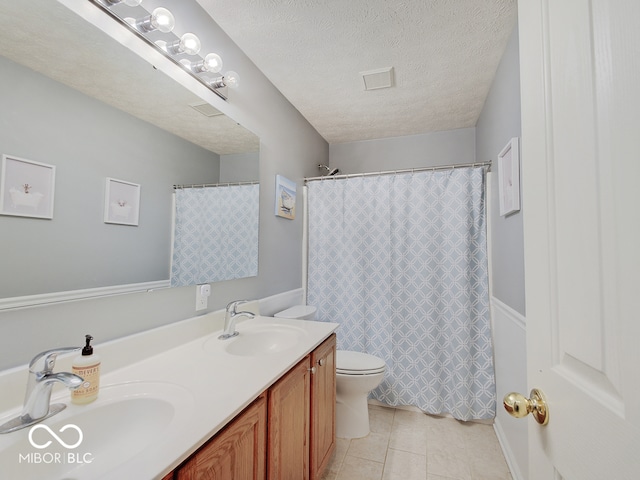 bathroom with vanity, a textured ceiling, tile patterned floors, and toilet