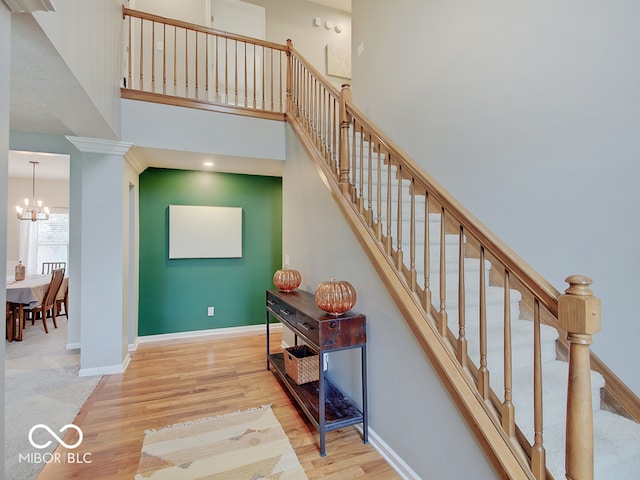 staircase featuring wood-type flooring, a towering ceiling, and an inviting chandelier