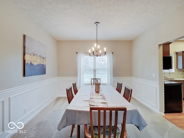 dining room featuring light hardwood / wood-style flooring, sink, a textured ceiling, and an inviting chandelier