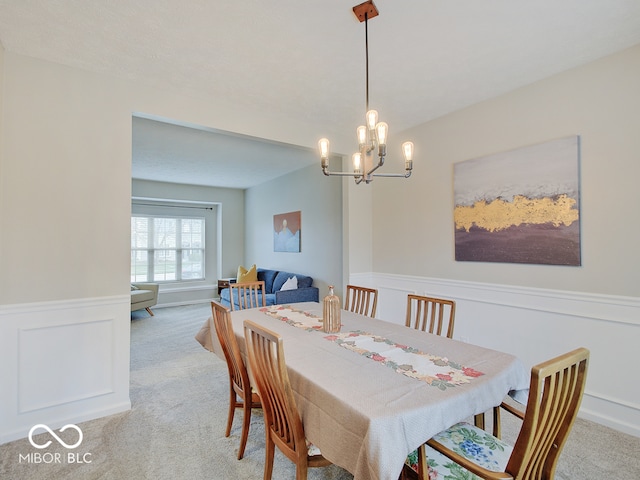 carpeted dining space with a chandelier