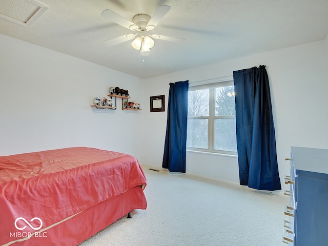 carpeted bedroom with ceiling fan and a textured ceiling