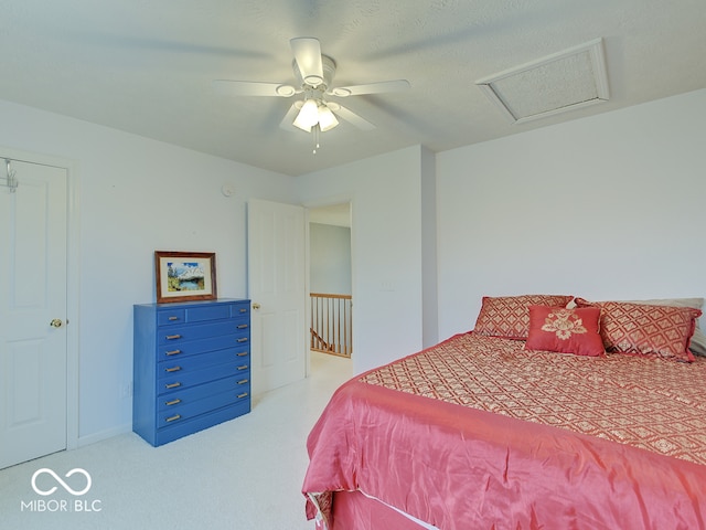 bedroom featuring ceiling fan, light carpet, and a textured ceiling