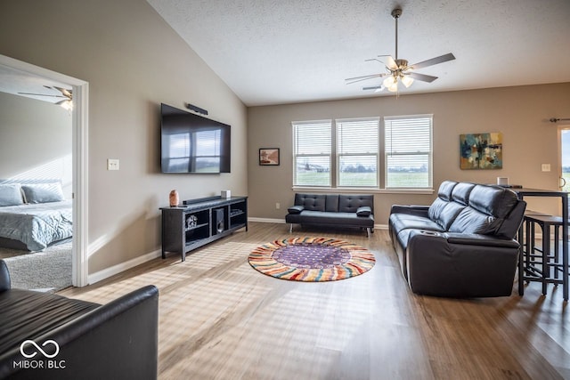 living room featuring a textured ceiling, hardwood / wood-style flooring, ceiling fan, and lofted ceiling