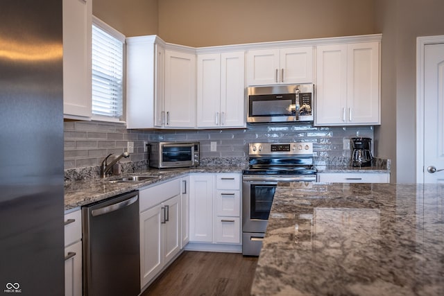 kitchen featuring stone counters, sink, white cabinets, and appliances with stainless steel finishes