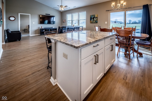 kitchen with white cabinetry, hanging light fixtures, dark hardwood / wood-style floors, vaulted ceiling, and a kitchen island