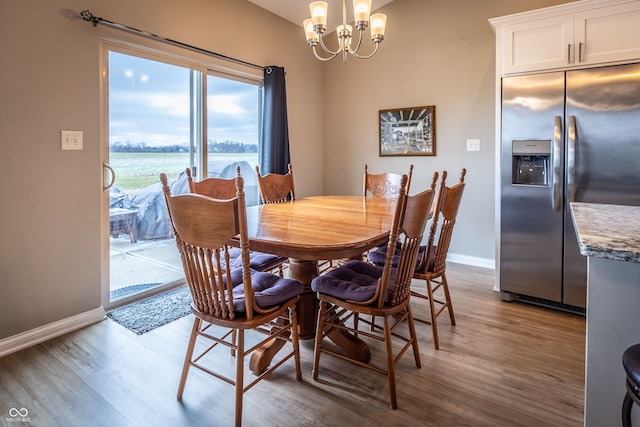 dining room with light hardwood / wood-style floors, an inviting chandelier, and a water view