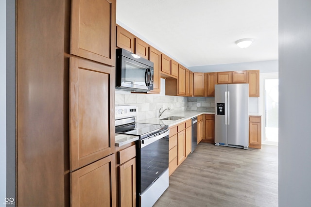 kitchen featuring appliances with stainless steel finishes, backsplash, light hardwood / wood-style floors, and sink