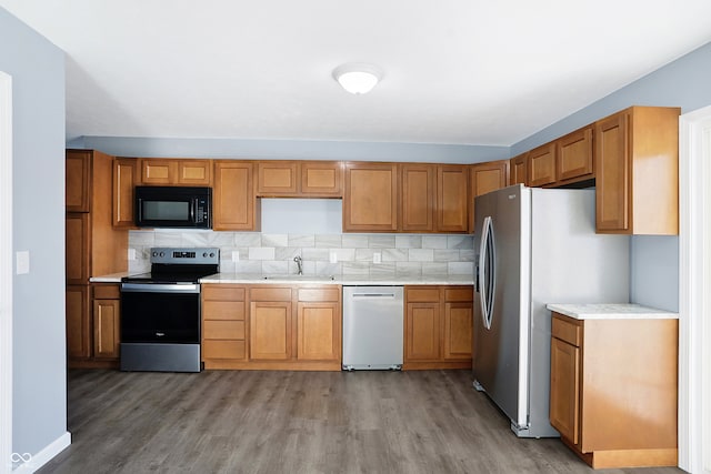 kitchen with appliances with stainless steel finishes, light wood-type flooring, tasteful backsplash, and sink