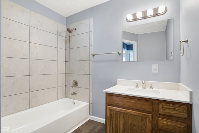 bathroom with hardwood / wood-style flooring, vanity, and tiled shower / bath