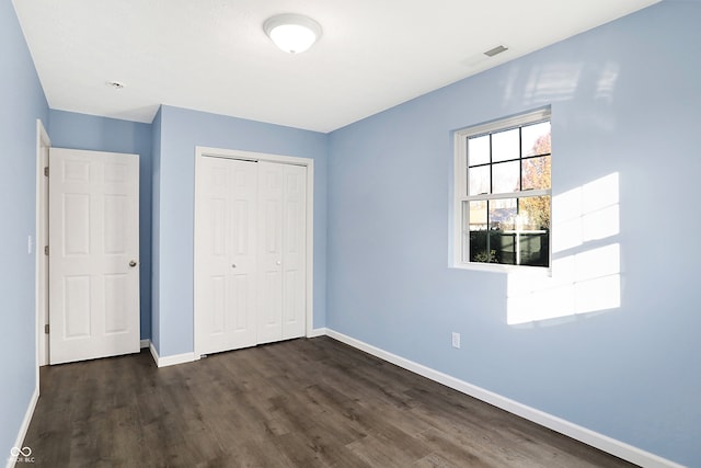 unfurnished bedroom featuring dark hardwood / wood-style flooring and a closet