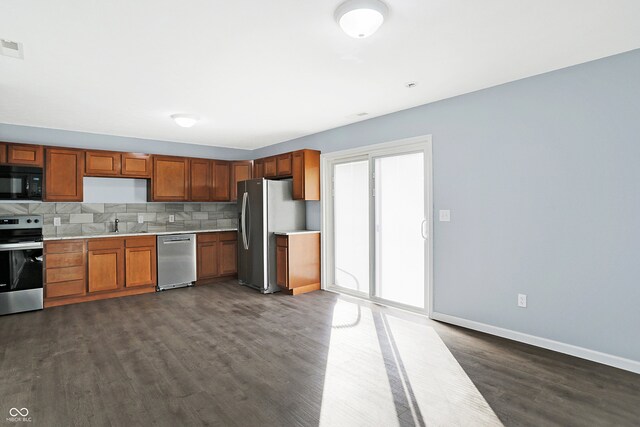 kitchen with dark wood-type flooring, stainless steel appliances, and tasteful backsplash