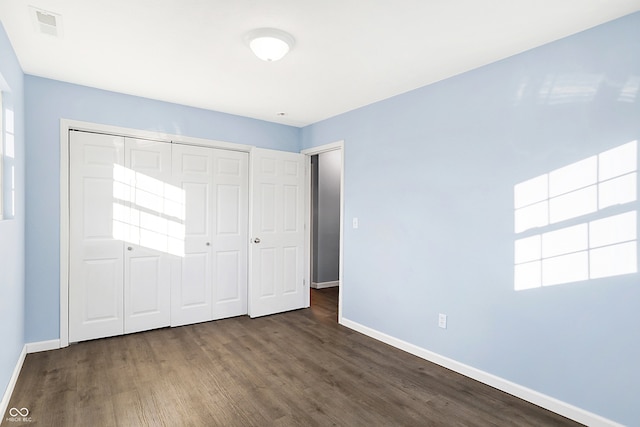 unfurnished bedroom with dark hardwood / wood-style floors and a closet