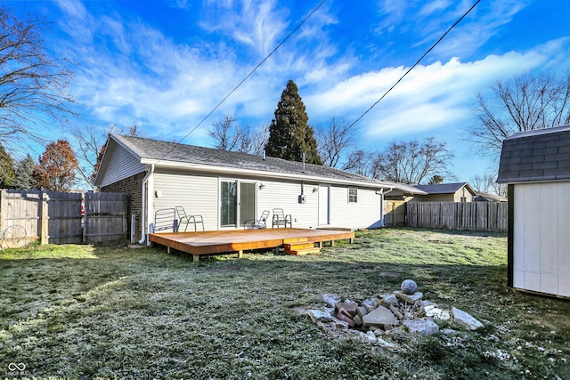 rear view of property with a shed, a lawn, and a wooden deck