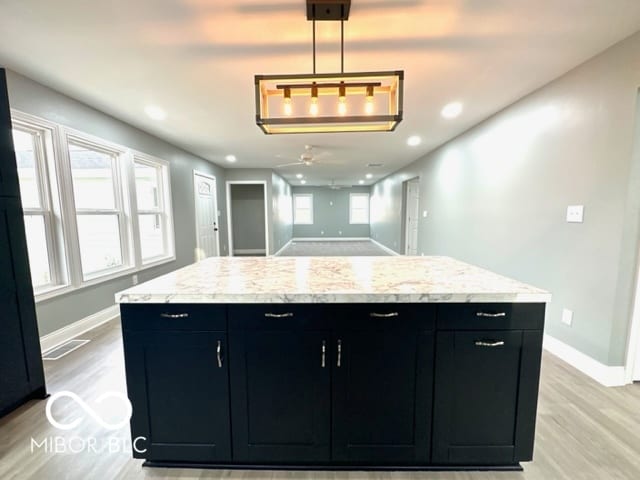 kitchen featuring ceiling fan, a healthy amount of sunlight, light hardwood / wood-style floors, and hanging light fixtures