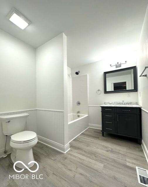 full bathroom featuring toilet, vanity, hardwood / wood-style flooring, and bathing tub / shower combination